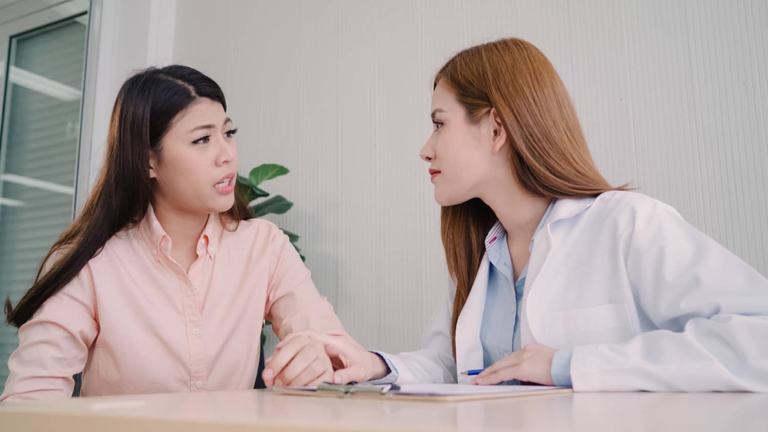 doctor talking unhappy teenage patient exam room